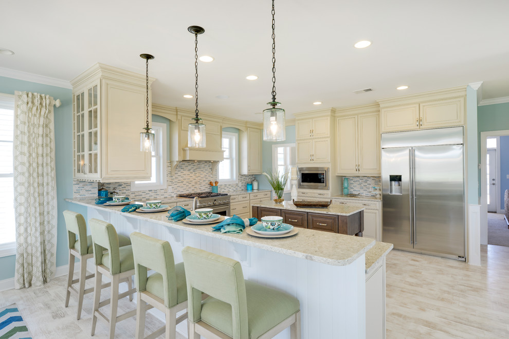 Example of a beach style light wood floor eat-in kitchen design in Philadelphia with a farmhouse sink, raised-panel cabinets, white cabinets, quartz countertops, multicolored backsplash, mosaic tile backsplash, stainless steel appliances and an island
