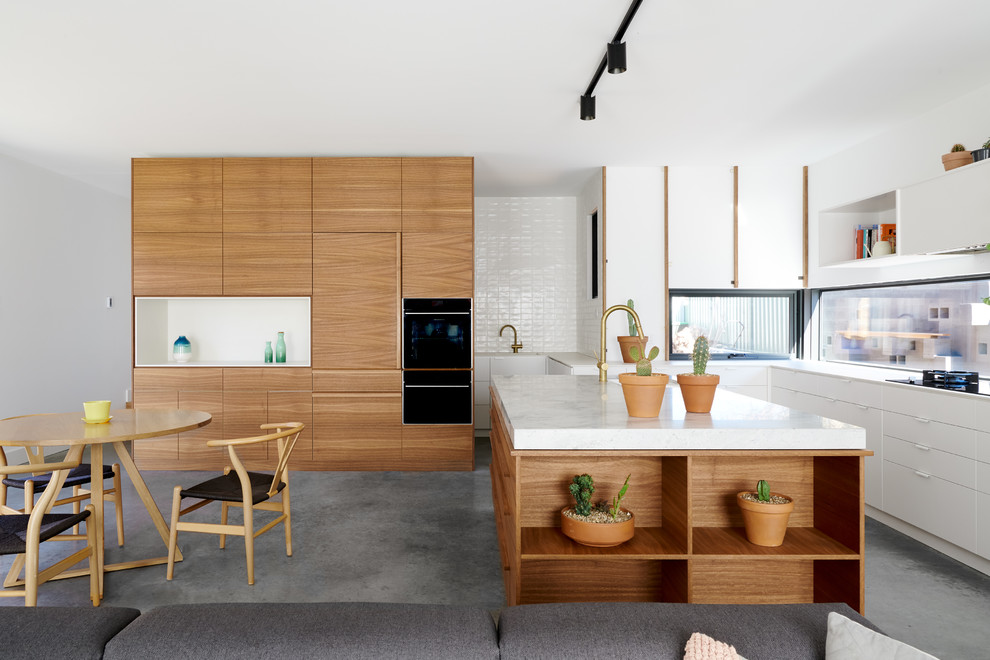 Design ideas for a contemporary l-shaped open plan kitchen in Canberra - Queanbeyan with flat-panel cabinets, white cabinets, window splashback, concrete flooring, an island, grey floors and white worktops.