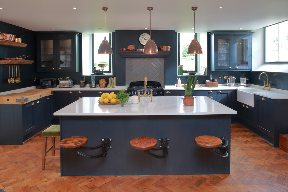 Foto di una cucina classica di medie dimensioni con lavello stile country, top in superficie solida, pavimento in legno massello medio, ante blu, paraspruzzi con piastrelle in ceramica, ante di vetro, paraspruzzi grigio, elettrodomestici neri e pavimento arancione