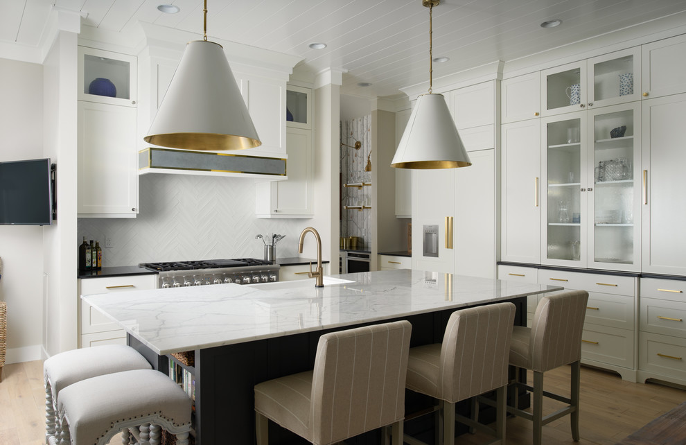 Kitchen - coastal light wood floor and beige floor kitchen idea in Boise with a farmhouse sink, shaker cabinets, white cabinets, white backsplash, an island, white countertops and paneled appliances