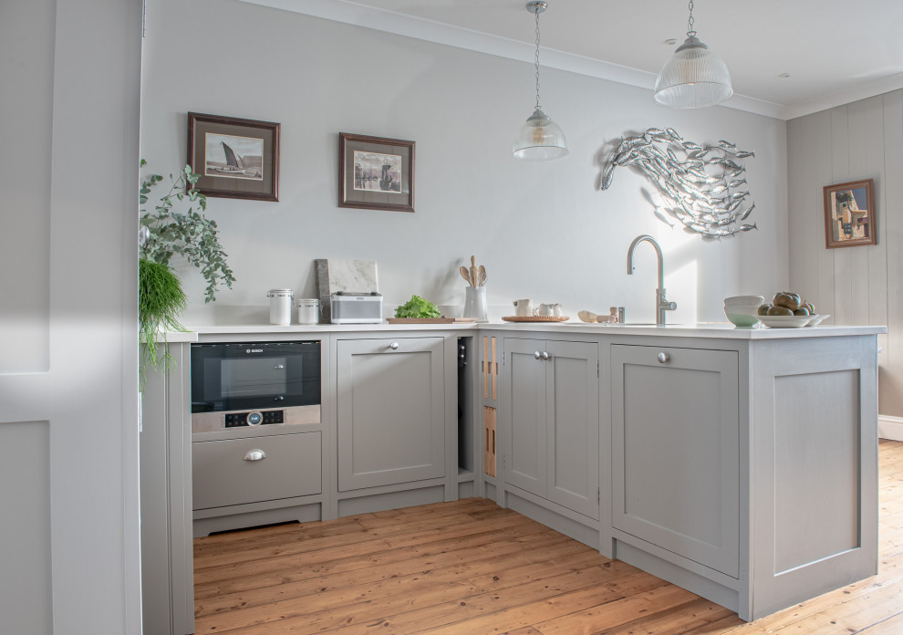 This is an example of a medium sized traditional u-shaped kitchen/diner in Surrey with a double-bowl sink, shaker cabinets, grey cabinets, quartz worktops, black appliances, no island and white worktops.