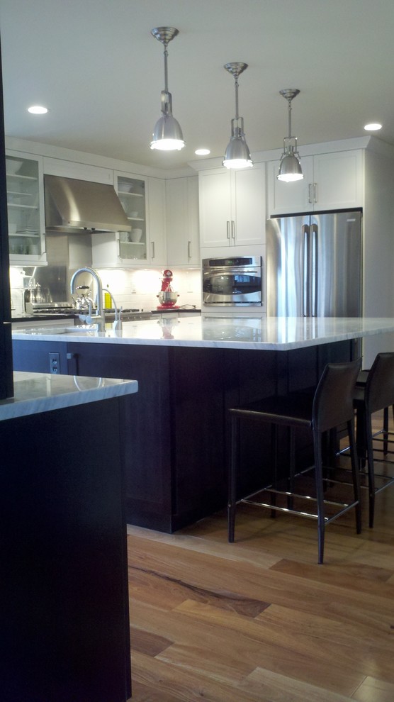 Example of a mid-sized minimalist l-shaped dark wood floor enclosed kitchen design in Other with an undermount sink, shaker cabinets, white cabinets, marble countertops, white backsplash, subway tile backsplash, stainless steel appliances and an island