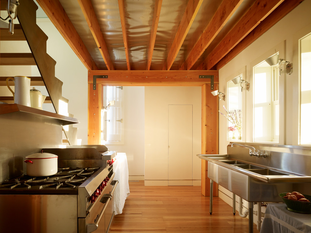 Inspiration for an urban galley enclosed kitchen in Minneapolis with stainless steel appliances and a triple-bowl sink.