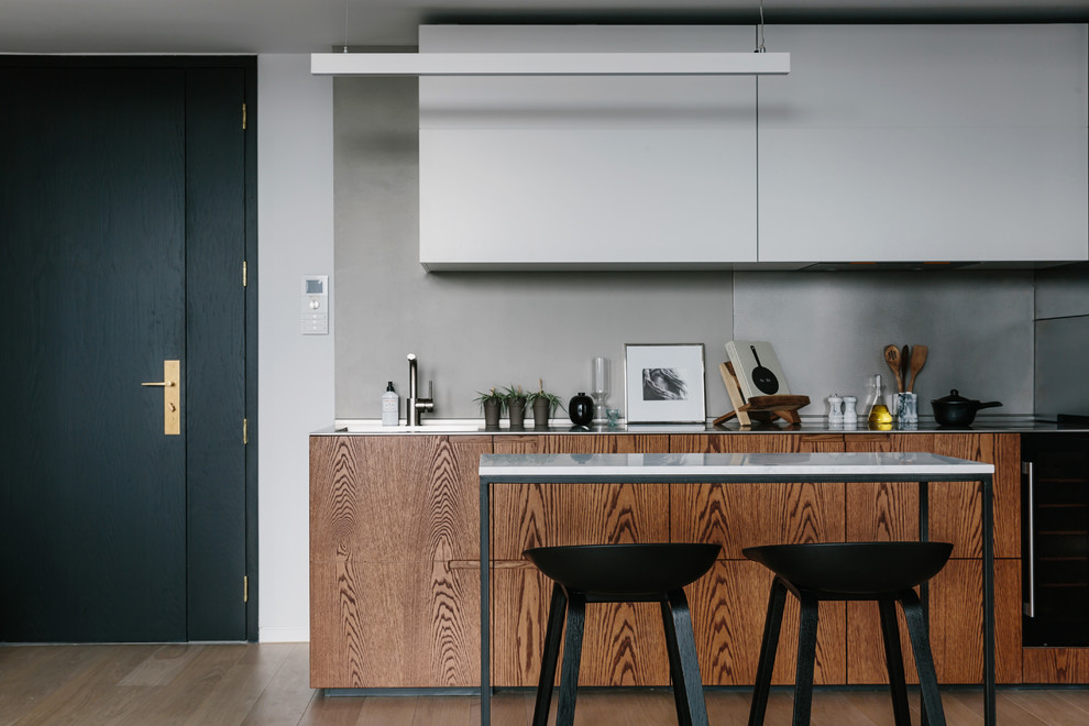 Imagen de cocina actual pequeña con puertas de armario de madera oscura, encimera de acero inoxidable, salpicadero de azulejos de cemento y península