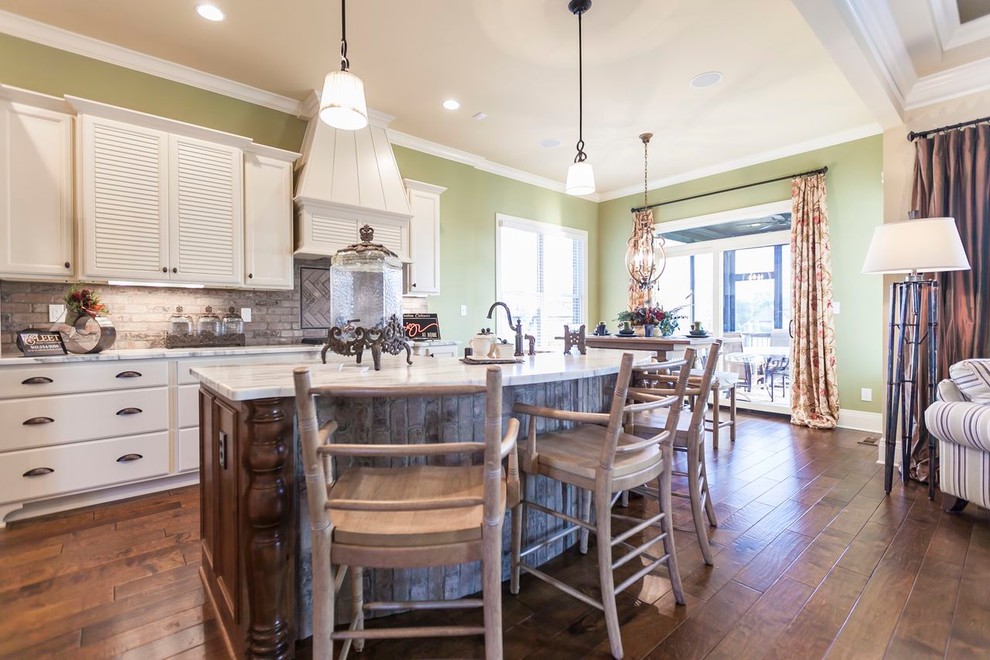 Inspiration for a mid-sized timeless l-shaped dark wood floor open concept kitchen remodel in Louisville with recessed-panel cabinets, white cabinets, marble countertops, beige backsplash, stainless steel appliances, an island and brick backsplash