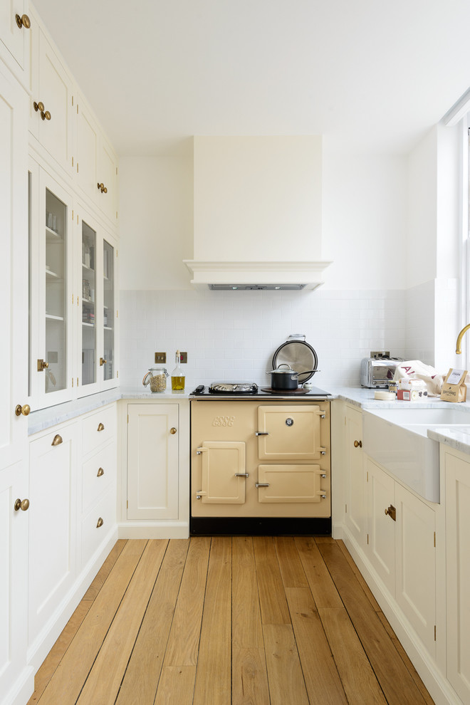 Bild på ett avskilt, litet funkis u-kök, med en rustik diskho, skåp i shakerstil, vita skåp, marmorbänkskiva, vitt stänkskydd, stänkskydd i tunnelbanekakel, färgglada vitvaror och mellanmörkt trägolv