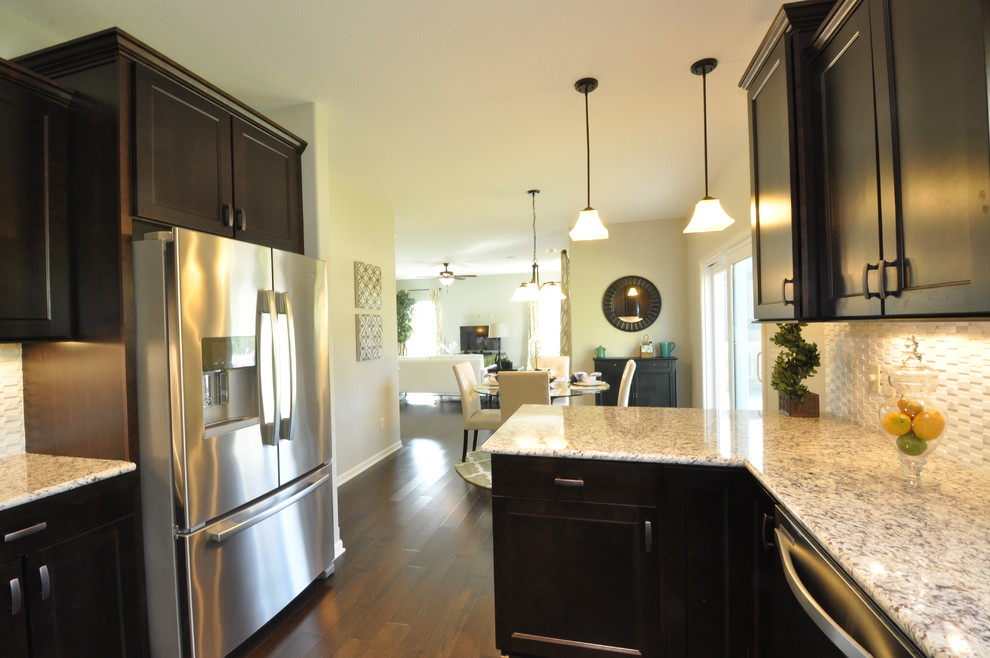 Mid-sized elegant u-shaped dark wood floor eat-in kitchen photo in Milwaukee with a double-bowl sink, recessed-panel cabinets, dark wood cabinets, granite countertops, white backsplash, matchstick tile backsplash, stainless steel appliances and a peninsula