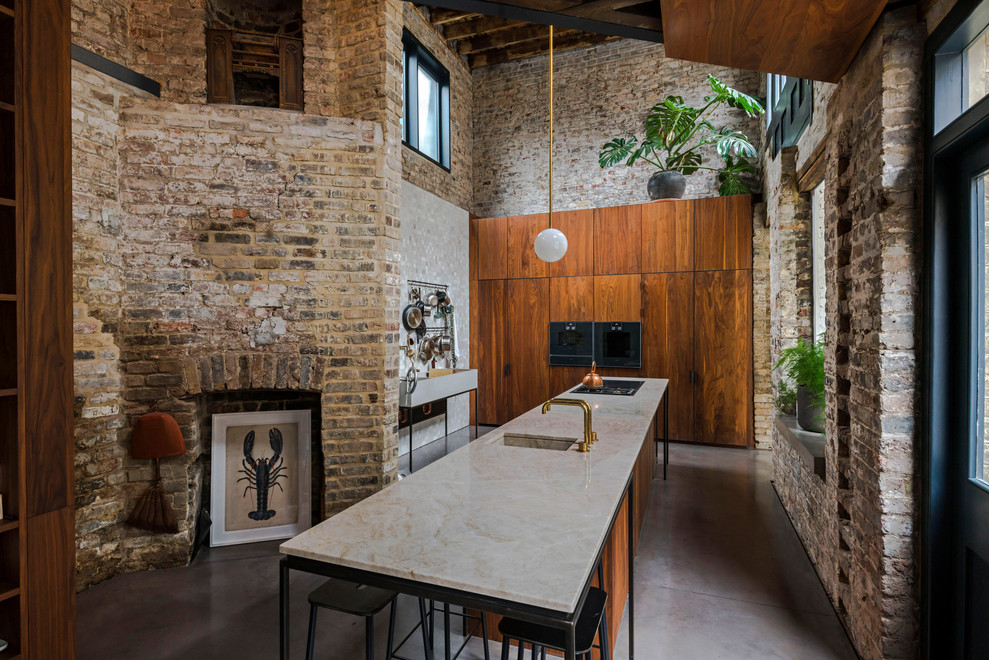 Inspiration for an industrial kitchen in London with a submerged sink, flat-panel cabinets, medium wood cabinets, stainless steel appliances, concrete flooring, an island, grey floors and white worktops.