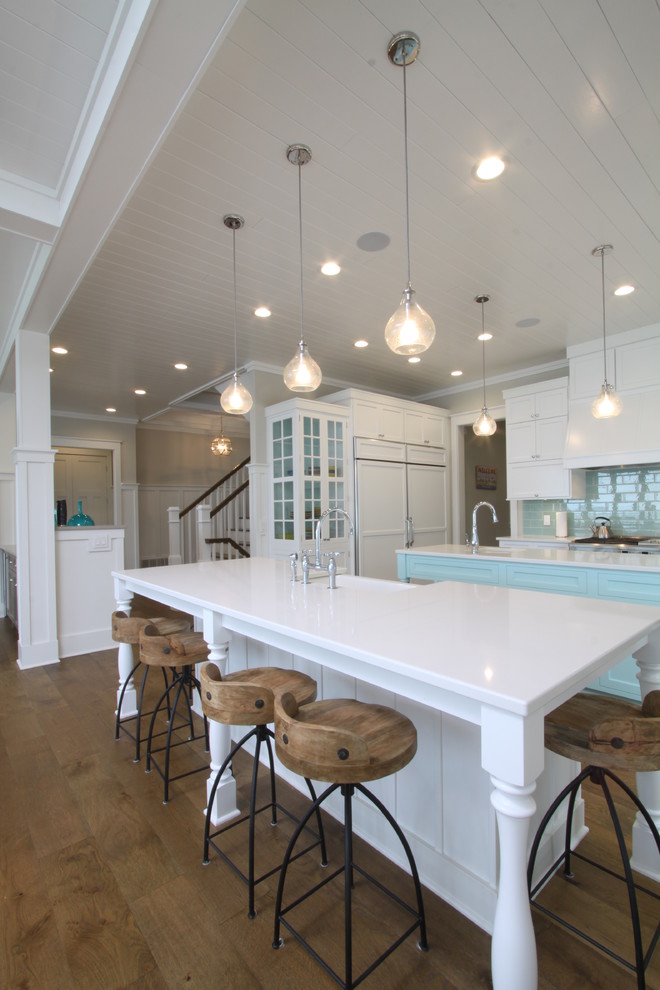 Inspiration for a large coastal l-shaped medium tone wood floor and brown floor open concept kitchen remodel in Grand Rapids with an undermount sink, shaker cabinets, white cabinets, quartz countertops, blue backsplash, subway tile backsplash, stainless steel appliances and two islands