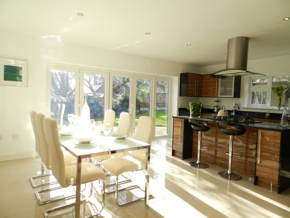 Moderne Wohnküche in L-Form mit Unterbauwaschbecken, Glasfronten, schwarzen Schränken, Granit-Arbeitsplatte, Küchenrückwand in Schwarz und Küchengeräten aus Edelstahl in Sonstige