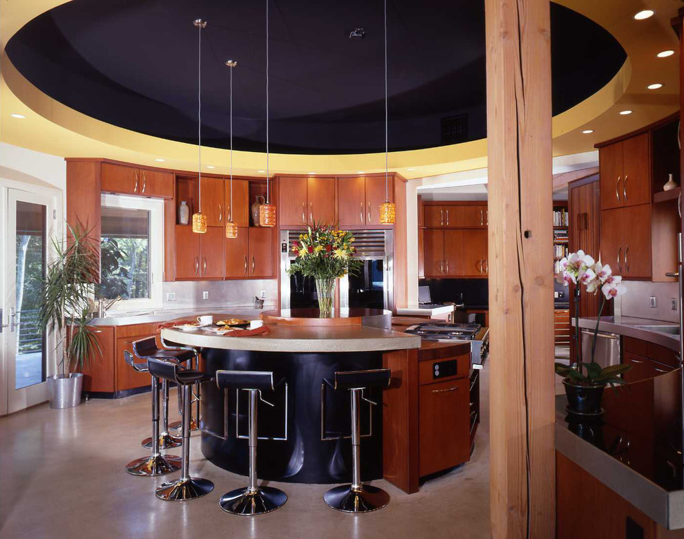 Example of a large country u-shaped concrete floor open concept kitchen design in Manchester with an integrated sink, flat-panel cabinets, medium tone wood cabinets, stainless steel countertops, stainless steel appliances and an island