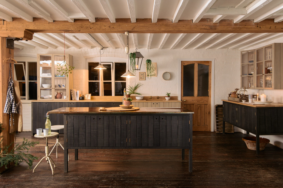 Imagen de cocina de estilo de casa de campo con armarios tipo vitrina, puertas de armario beige, suelo de madera oscura y una isla