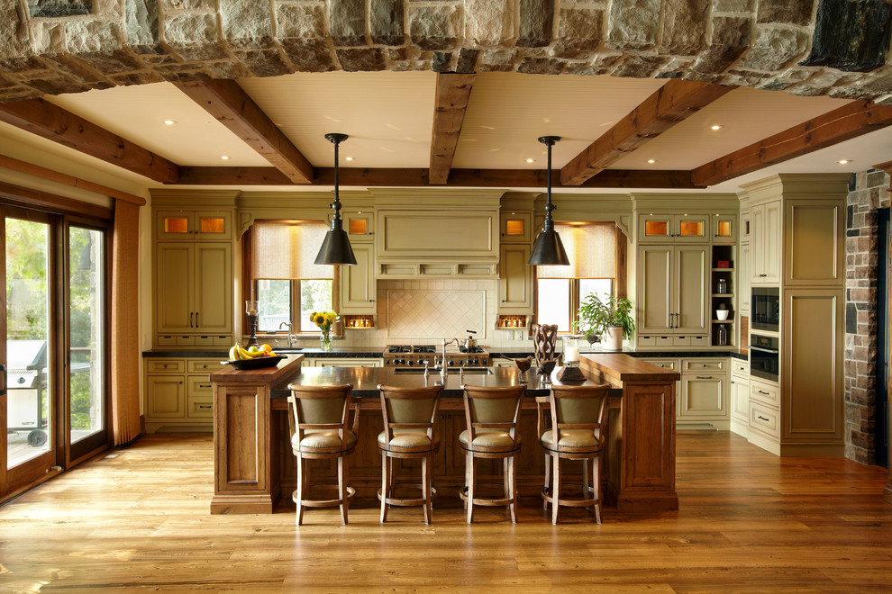 Large rustic u-shaped kitchen/diner in Toronto with a belfast sink, recessed-panel cabinets, granite worktops, beige splashback, porcelain splashback, stainless steel appliances, medium hardwood flooring and an island.