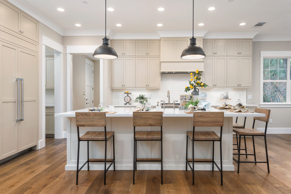 Photo of a traditional l-shaped kitchen in San Francisco with shaker cabinets, beige cabinets, white splashback, integrated appliances, dark hardwood flooring, an island and brown floors.