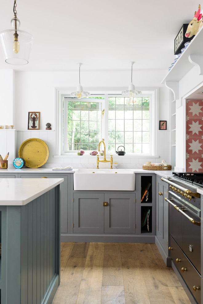 Foto på ett mellanstort lantligt kök, med en dubbel diskho, skåp i shakerstil, grå skåp, orange stänkskydd, stänkskydd i keramik, rostfria vitvaror, mellanmörkt trägolv, en köksö och brunt golv