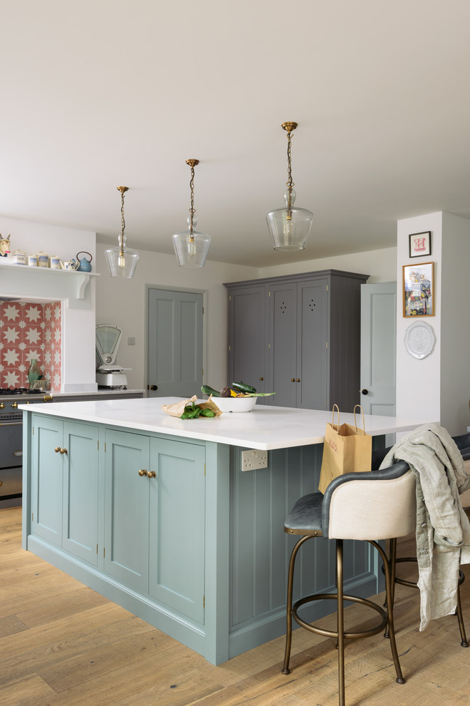 Mid-sized farmhouse l-shaped medium tone wood floor eat-in kitchen photo in Other with a double-bowl sink, shaker cabinets, gray cabinets, orange backsplash, ceramic backsplash, stainless steel appliances and an island