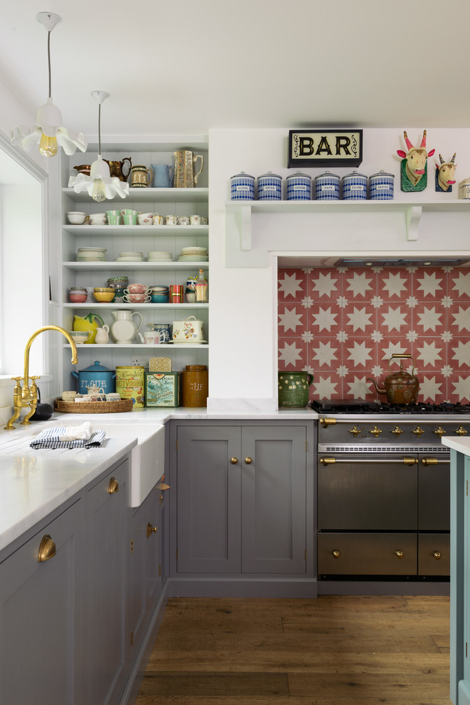 Mid-sized country l-shaped medium tone wood floor and brown floor eat-in kitchen photo in Other with a double-bowl sink, shaker cabinets, gray cabinets, orange backsplash, ceramic backsplash, stainless steel appliances and an island