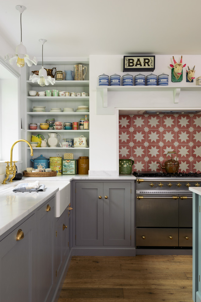 Bild på ett mellanstort lantligt kök, med en dubbel diskho, skåp i shakerstil, grå skåp, orange stänkskydd, stänkskydd i keramik, rostfria vitvaror, mellanmörkt trägolv, en köksö och brunt golv