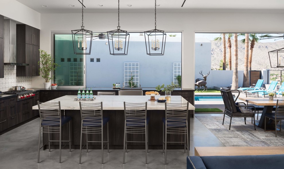 Eat-in kitchen - contemporary l-shaped concrete floor and gray floor eat-in kitchen idea in Phoenix with a farmhouse sink, flat-panel cabinets, dark wood cabinets, multicolored backsplash, stainless steel appliances, an island and white countertops