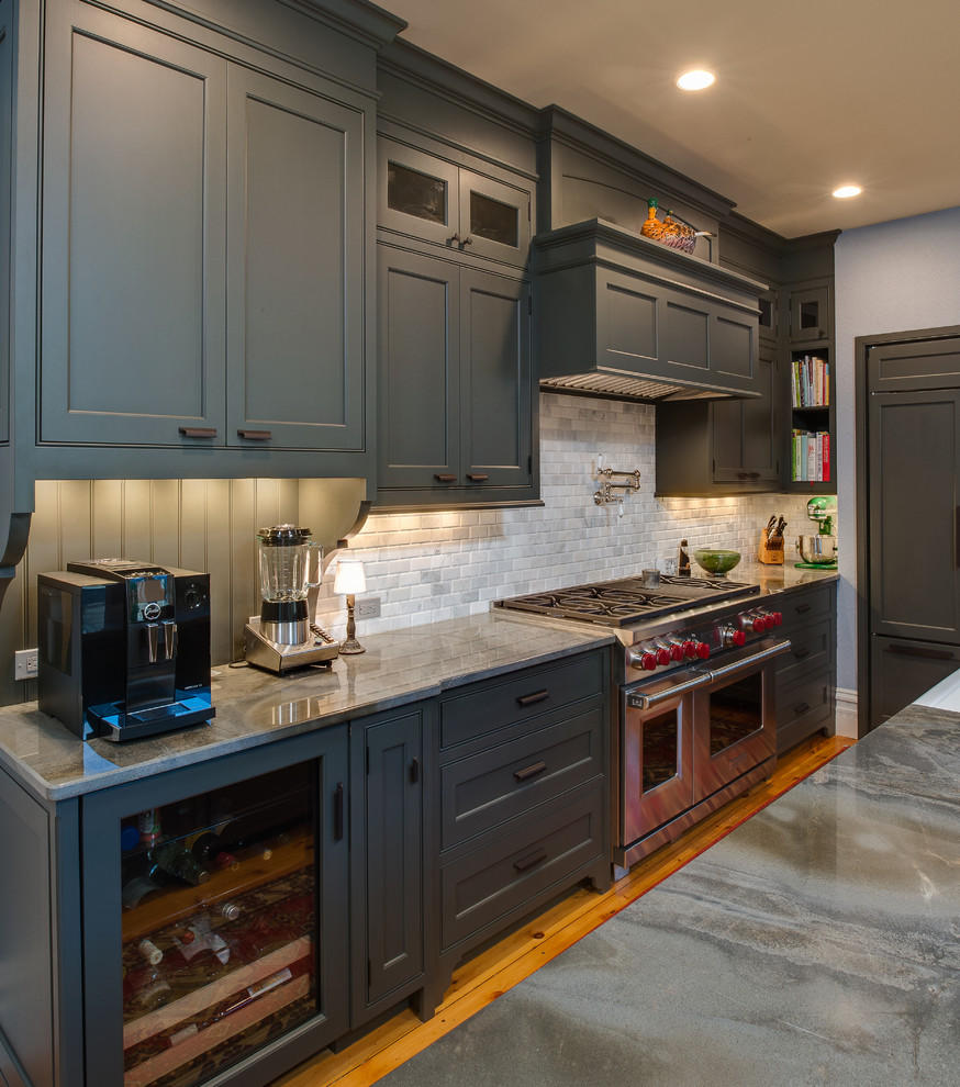 Inspiration for a large eclectic single-wall medium tone wood floor enclosed kitchen remodel in Other with a farmhouse sink, beaded inset cabinets, gray cabinets, granite countertops, gray backsplash, stone tile backsplash, stainless steel appliances and an island