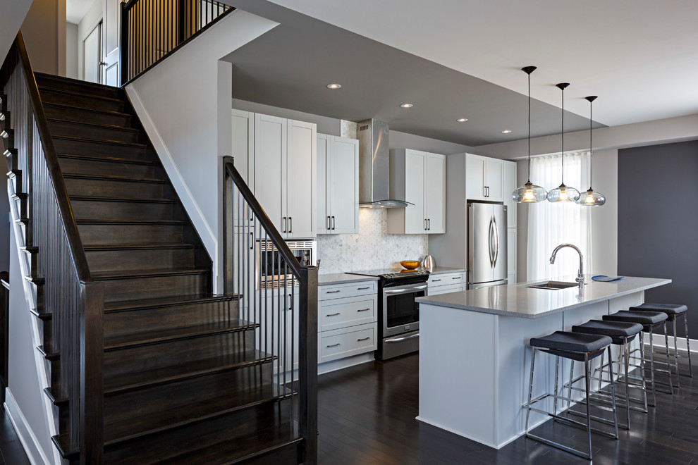 Kitchen - contemporary dark wood floor kitchen idea in Ottawa with an undermount sink, recessed-panel cabinets, white cabinets, white backsplash, stainless steel appliances and an island
