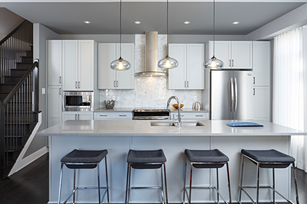 Example of a trendy dark wood floor kitchen design in Toronto with an undermount sink, recessed-panel cabinets, white cabinets, white backsplash, stainless steel appliances and an island