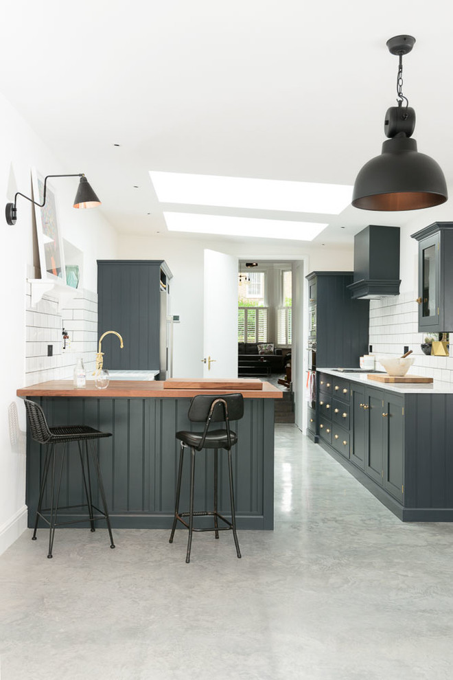 Inspiration for a traditional kitchen in London with recessed-panel cabinets, blue cabinets, wood worktops, white splashback, metro tiled splashback and a breakfast bar.