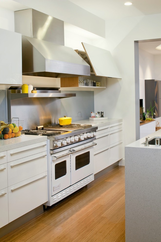 Foto de cocina minimalista con puertas de armario blancas, salpicadero metalizado y salpicadero de metal