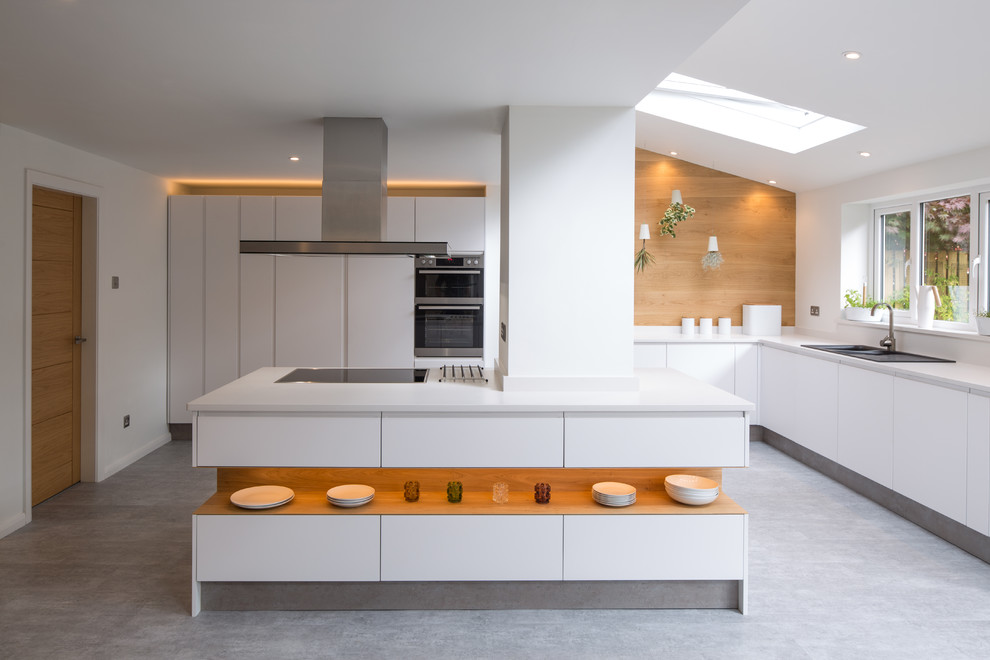 Diseño de cocinas en L contemporánea con fregadero encastrado, armarios con paneles lisos, puertas de armario blancas, electrodomésticos de acero inoxidable y una isla