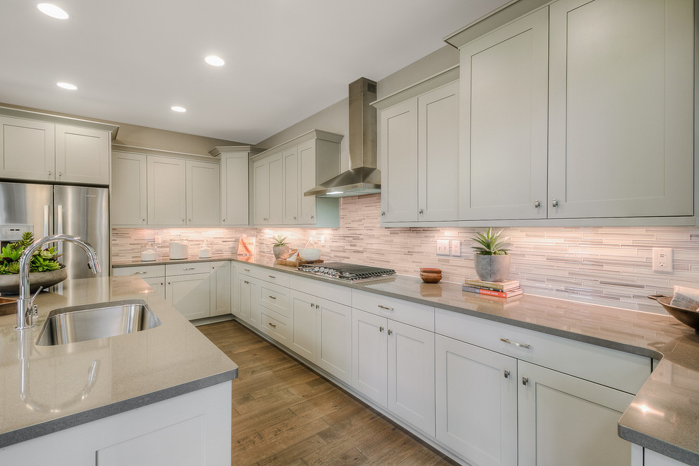 Inspiration for a classic u-shaped open plan kitchen in Seattle with a submerged sink, shaker cabinets, white cabinets, engineered stone countertops, white splashback, mosaic tiled splashback, stainless steel appliances, dark hardwood flooring and an island.
