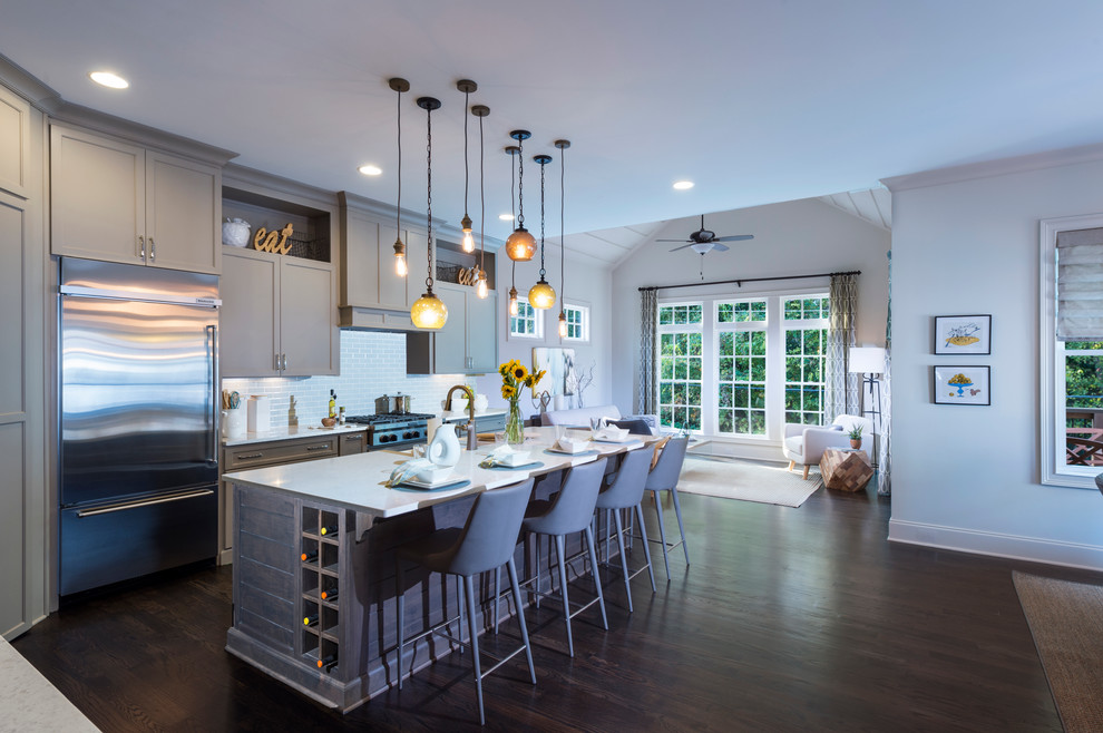 This is an example of a large kitchen in Atlanta with a belfast sink, recessed-panel cabinets, grey cabinets, grey splashback, metro tiled splashback, stainless steel appliances, dark hardwood flooring and an island.