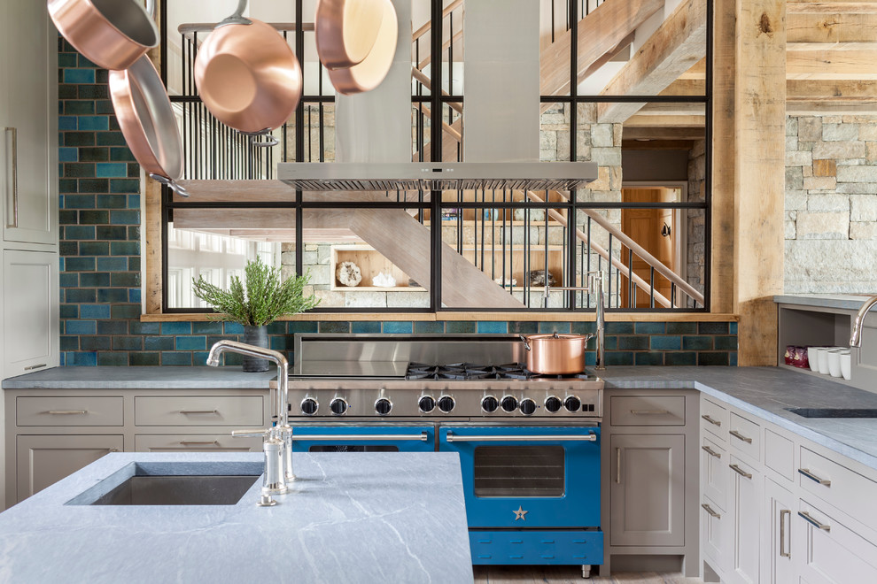 Bild på ett stort industriellt kök, med en undermonterad diskho, luckor med infälld panel, grå skåp, marmorbänkskiva, blått stänkskydd, stänkskydd i keramik, färgglada vitvaror, ljust trägolv och en köksö