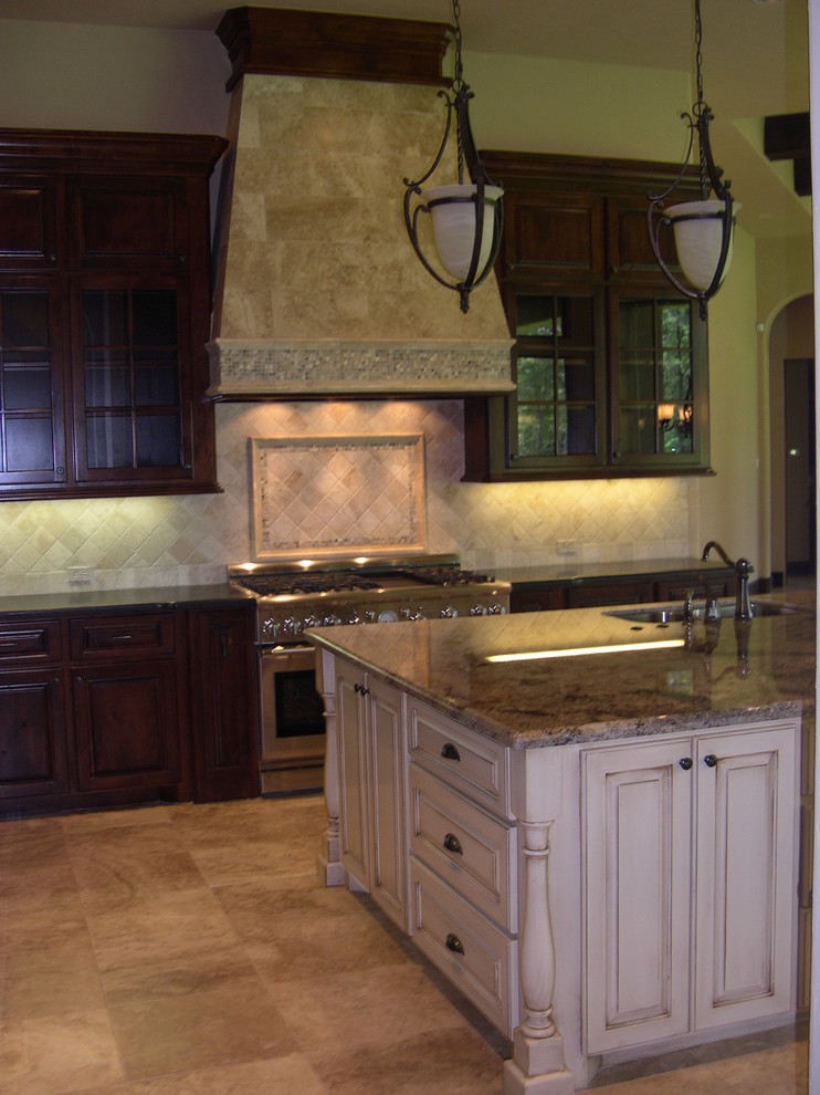 Inredning av ett klassiskt stort kök, med en undermonterad diskho, luckor med upphöjd panel, skåp i mörkt trä, granitbänkskiva, beige stänkskydd, stänkskydd i stenkakel, rostfria vitvaror, travertin golv och en köksö