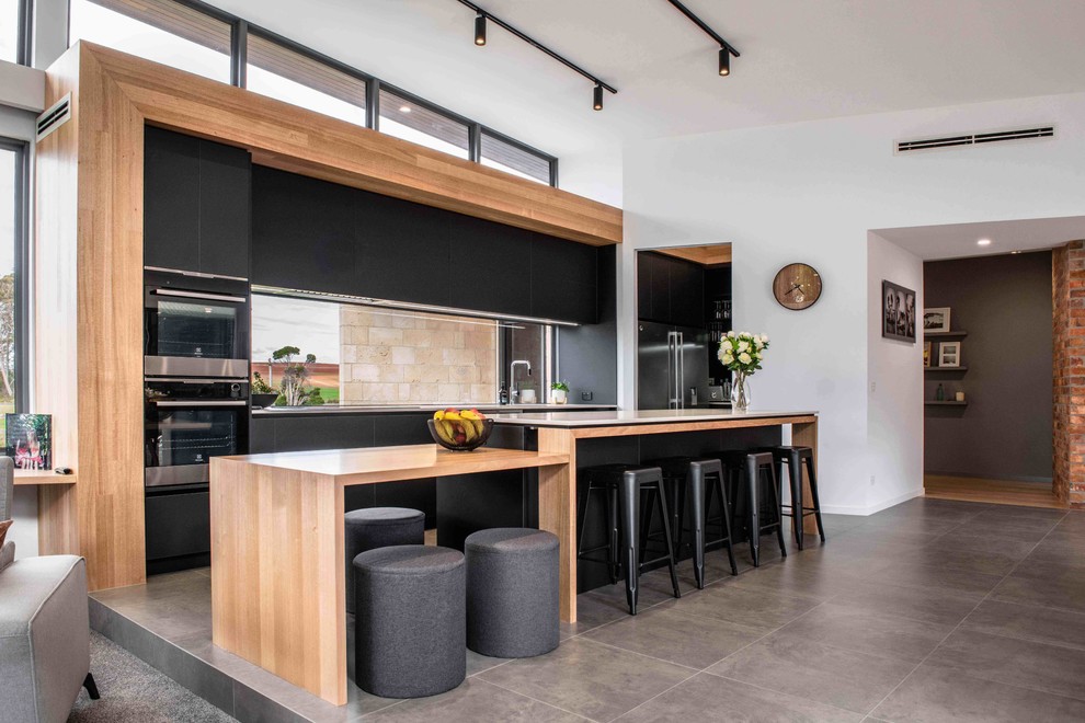 Inspiration for a contemporary gray floor open concept kitchen remodel in Other with an undermount sink, flat-panel cabinets, black cabinets, window backsplash, black appliances, an island and white countertops