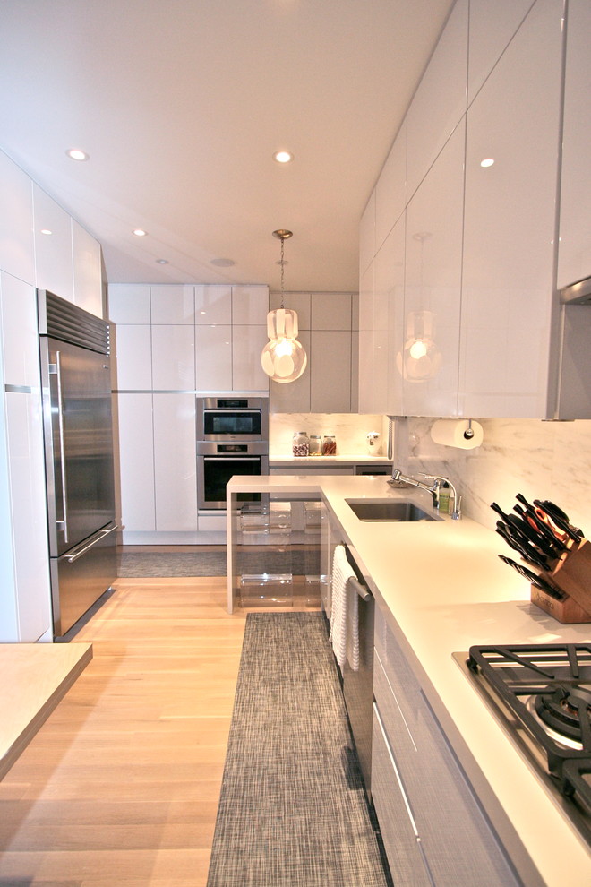 Moderne Küche mit Unterbauwaschbecken, flächenbündigen Schrankfronten, weißen Schränken und Küchengeräten aus Edelstahl in New York