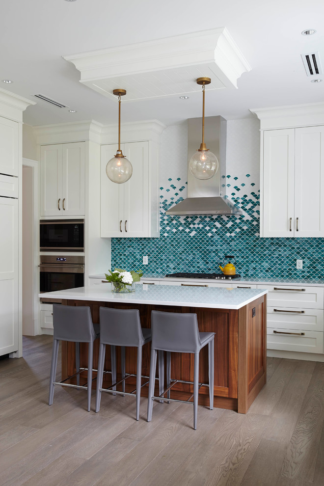 Transitional medium tone wood floor kitchen photo in Vancouver with shaker cabinets, white cabinets, blue backsplash, mosaic tile backsplash, stainless steel appliances and an island
