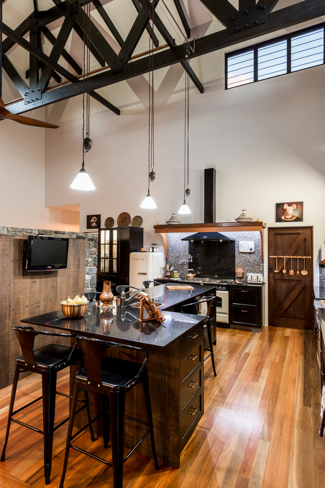 Example of a farmhouse kitchen design in Brisbane with a drop-in sink, dark wood cabinets, white appliances and an island
