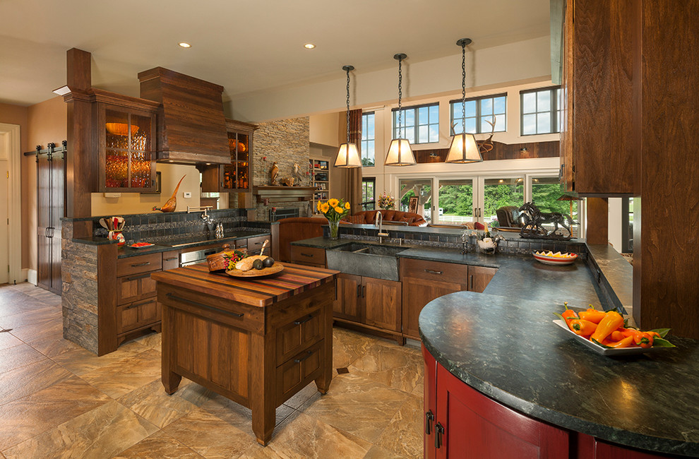 Traditional u-shaped open plan kitchen in Portland Maine with a belfast sink, glass-front cabinets, dark wood cabinets, multi-coloured splashback, stainless steel appliances and an island.
