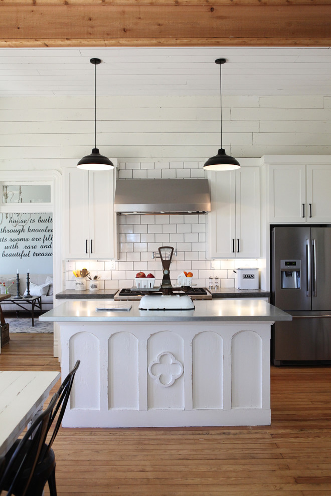 Inspiration for a mid-sized farmhouse medium tone wood floor kitchen remodel in Austin with a farmhouse sink, concrete countertops, white backsplash, subway tile backsplash, stainless steel appliances and an island