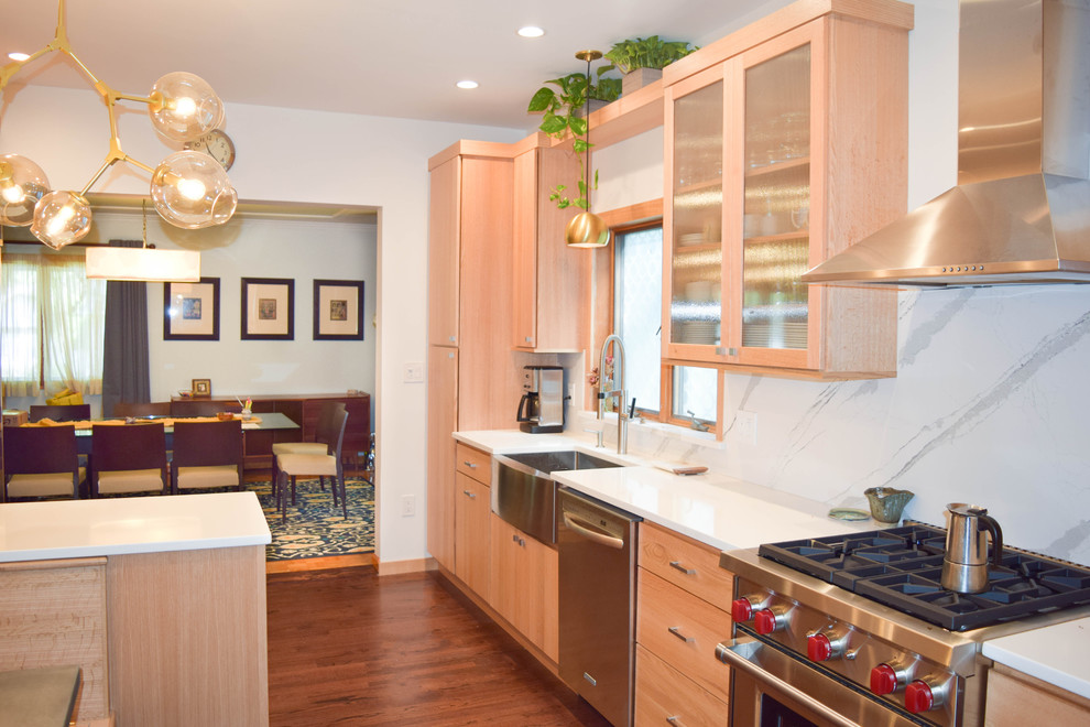 Bild på ett litet funkis kök, med en rustik diskho, släta luckor, skåp i ljust trä, bänkskiva i kvarts, vitt stänkskydd, rostfria vitvaror, mörkt trägolv och en halv köksö