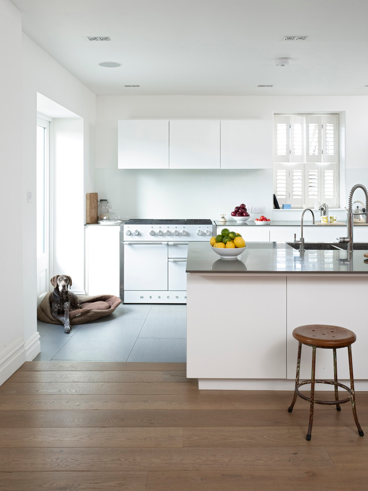 Foto de cocina contemporánea con fregadero de doble seno, puertas de armario blancas, suelo de madera clara y una isla