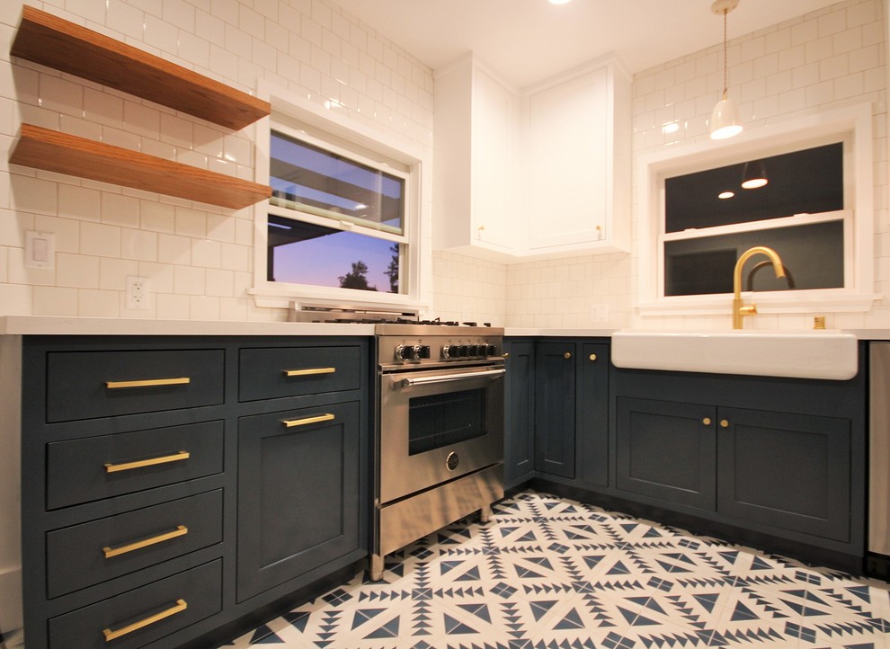 ロサンゼルスにある高級な小さなエクレクティックスタイルのおしゃれなキッチン (エプロンフロントシンク、シェーカースタイル扉のキャビネット、青いキャビネット、クオーツストーンカウンター、白いキッチンパネル、セラミックタイルのキッチンパネル、シルバーの調理設備、セメントタイルの床、白い床) の写真