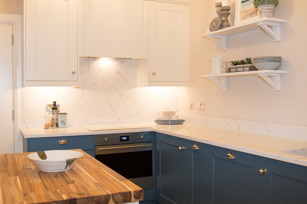 Small coastal l-shaped open plan kitchen in Other with a submerged sink, beaded cabinets, blue cabinets, quartz worktops, white splashback, stone slab splashback, stainless steel appliances, ceramic flooring, an island, brown floors and white worktops.