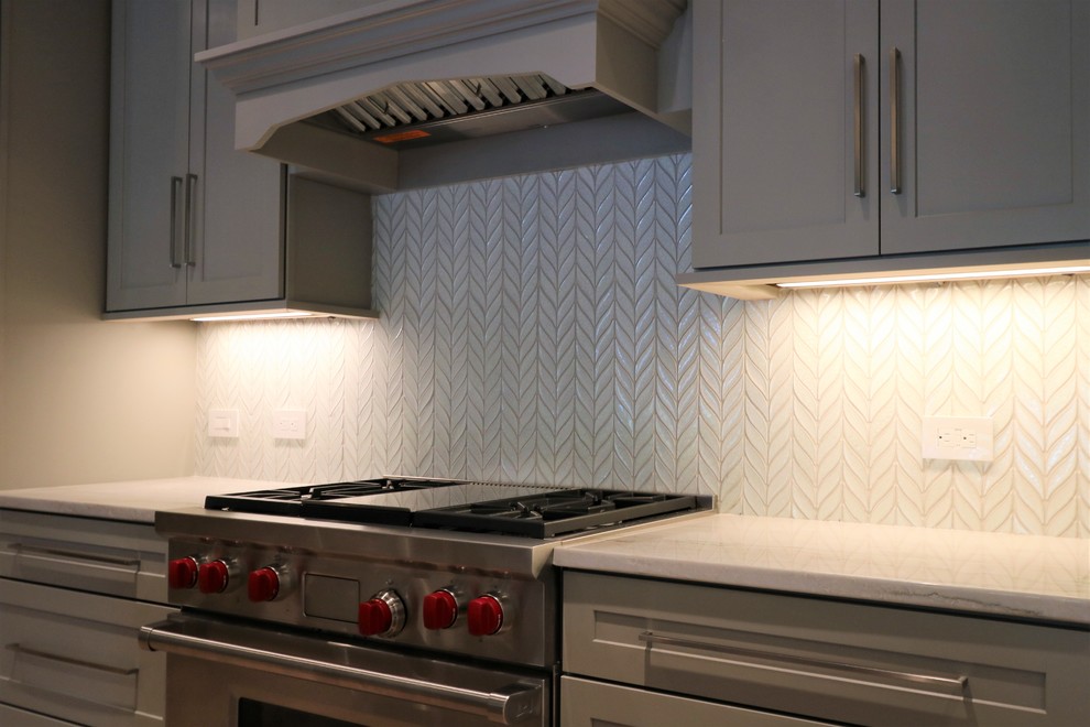 Example of a trendy single-wall kitchen design in Other with white backsplash, glass tile backsplash, stainless steel appliances and an island