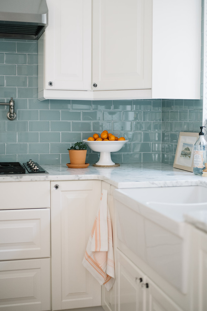 Exempel på ett mellanstort lantligt vit vitt kök, med en rustik diskho, luckor med upphöjd panel, vita skåp, marmorbänkskiva, blått stänkskydd, stänkskydd i glaskakel, rostfria vitvaror, mörkt trägolv, en köksö och brunt golv