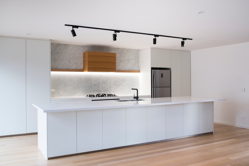Zweizeilige, Große Moderne Küche mit Unterbauwaschbecken, weißen Schränken, Quarzwerkstein-Arbeitsplatte, schwarzen Elektrogeräten, hellem Holzboden und Kücheninsel in Canberra - Queanbeyan