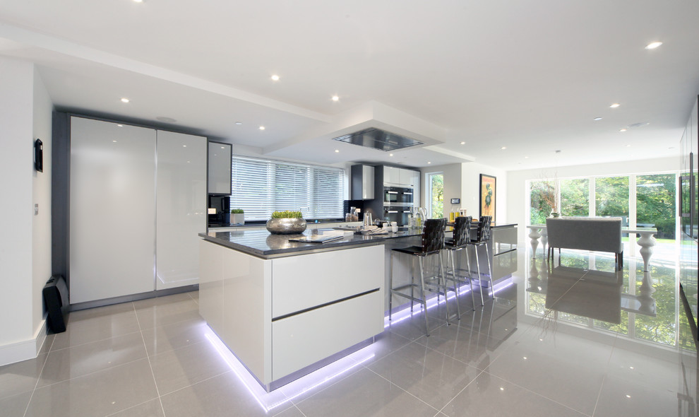 Contemporary kitchen/diner in Surrey with flat-panel cabinets, white cabinets, an island, grey floors and grey worktops.
