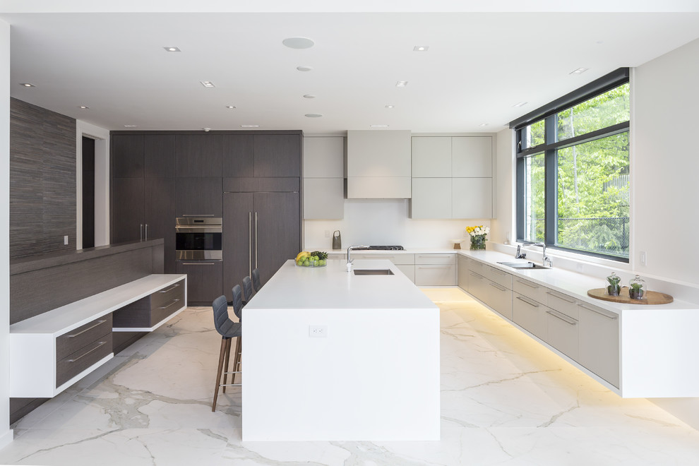 Foto på ett funkis kök, med en undermonterad diskho, släta luckor, grå skåp, vitt stänkskydd, integrerade vitvaror, marmorgolv, en köksö och vitt golv