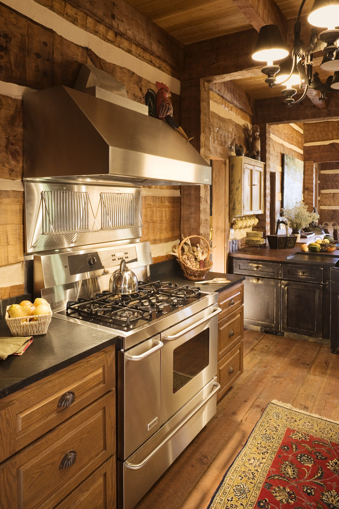Modelo de cocina rústica grande con puertas de armario de madera en tonos medios, electrodomésticos de acero inoxidable, armarios con paneles con relieve, salpicadero marrón y suelo de madera en tonos medios
