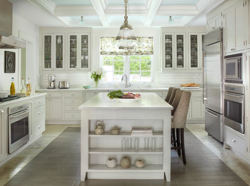 Klassische Küche mit Glasfronten, weißen Schränken, Küchenrückwand in Weiß, Rückwand aus Metrofliesen und Küchengeräten aus Edelstahl in St. Louis